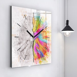 May include: A square clock featuring a colourful brain design. The left side of the brain is drawn in black and white with a detailed design. The right side of the brain is filled with colourful watercolour paint splatters.