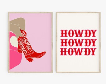 Op de afbeelding: Twee ingelijste kunstprints. Eén toont een rode cowboylaars met witte details op een roze achtergrond. De andere print heeft het woord "HOWDY" driemaal in rood op een witte achtergrond. Beide prints hebben een licht houten frame.