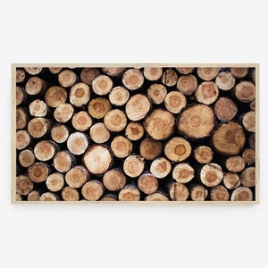 May include: A close-up of a pile of stacked wood logs, showing the natural grain and texture of the wood. The logs are arranged in a random pattern, creating a rustic and organic look.