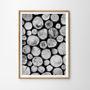 May include: Black and white photograph of a stack of round wooden logs. The logs are arranged in a random pattern, creating a textured and organic look.