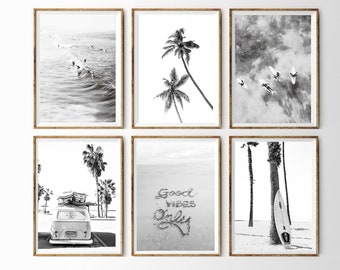 Könnte beinhalten: Sechs Schwarzweißfotos in Holzrahmen, die eine Strandszene mit Palmen, Surfern und einem Vintage-Van zeigen. Der Text "Good Vibes Only" ist auf einem der Fotos in den Sand geschrieben.