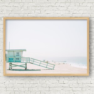 May include: A framed photograph of a light blue lifeguard stand on a beach with a pier in the distance. The stand has the number "40" on it.