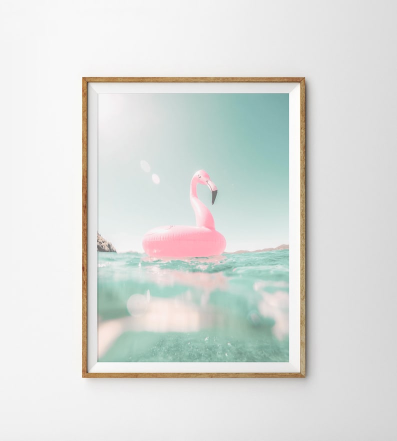 May include: A pink flamingo inflatable pool float in a turquoise blue body of water. The water is clear and you can see the bottom of the pool. The sky is a light blue.