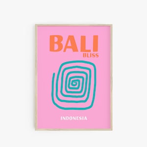 Op de afbeelding: Een roze poster met de tekst "BALI BLISS" in oranje en "INDONESIA" in zwart. In het midden van de poster staat een turquoise spiraalvormig ontwerp.