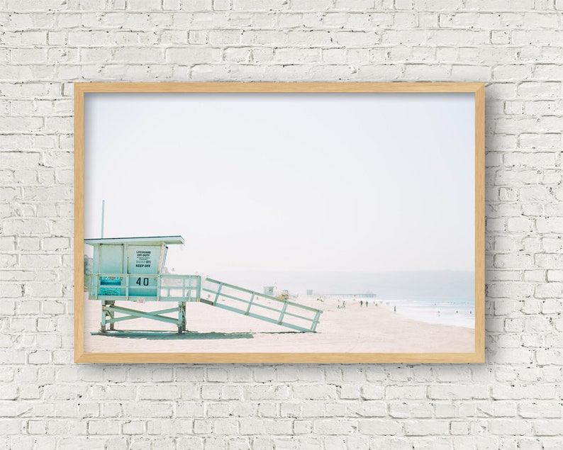 May include: A framed photograph of a light blue lifeguard stand on a beach with a pier in the distance. The stand has the number "40" on it.