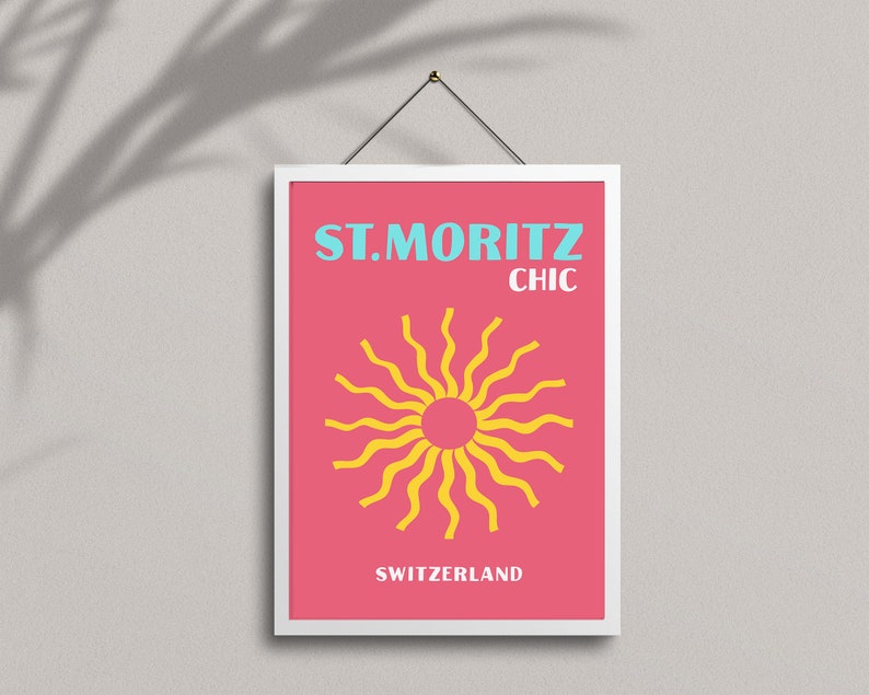 May include: A pink and white framed poster with the text "ST. MORITZ CHIC" in blue and yellow. The poster features a yellow sun with wavy rays on a pink background. The text "SWITZERLAND" is at the bottom of the poster.