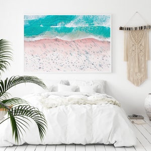 Op de afbeelding: Een luchtfoto van een strand met turquoise water en wit zand. Het strand is druk met mensen en de schaduwen van de mensen zijn zichtbaar in het zand.