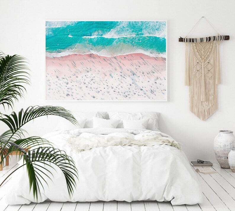 Op de afbeelding: Een luchtfoto van een strand met turquoise water en wit zand. Het strand is druk met mensen en de schaduwen van de mensen zijn zichtbaar in het zand.