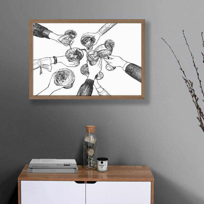 Pu&ograve; includere: Disegno in bianco e nero di un gruppo di persone che alzano i bicchieri per un brindisi. L'immagine &egrave; incorniciata in una cornice di legno marrone chiaro.