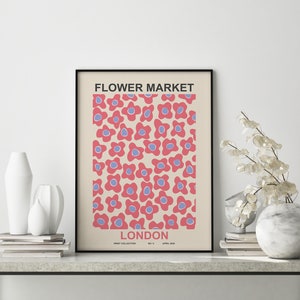 Pu&ograve; includere: Un poster incorniciato nero con sfondo crema e un motivo ripetitivo di fiori rosa e blu. Il poster dice "FLOWER MARKET LONDON" e "PRINT COLLECTION NO. 5 APRIL 2020".