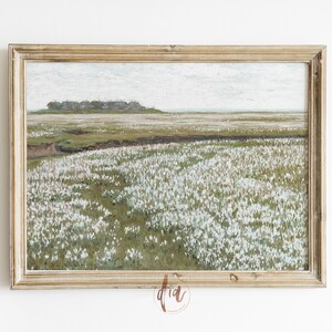 May include: A framed painting depicting a landscape with a field of white flowers in the foreground, a small group of houses in the distance, and a cloudy sky.