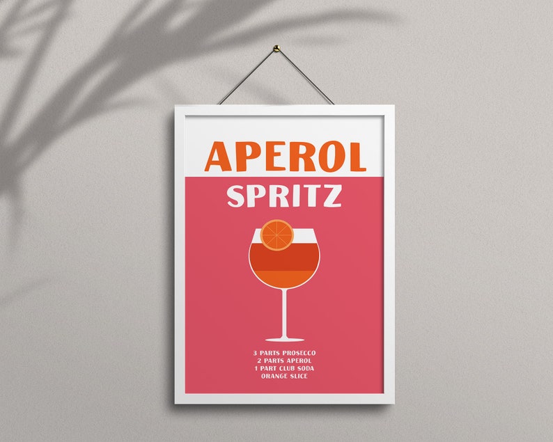 Pode incluir: Um p&ocirc;ster emoldurado branco com fundo rosa e o texto "Aperol Spritz" em laranja e branco. Um copo de Aperol Spritz com uma fatia de laranja &eacute; mostrado no centro. Os ingredientes s&atilde;o listados abaixo do copo: 3 partes de Prosecco, 2 partes de Aperol, 1 parte de &aacute;gua com g&aacute;s, fatia de laranja.