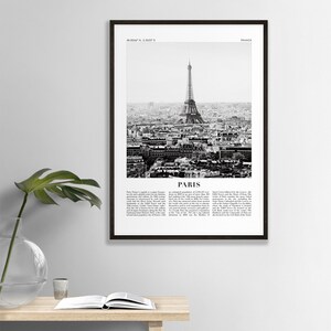 May include: A black and white photograph of the Eiffel Tower in Paris, France. The image shows the tower from a distance, with the city of Paris in the background. The image is framed in a black frame.
