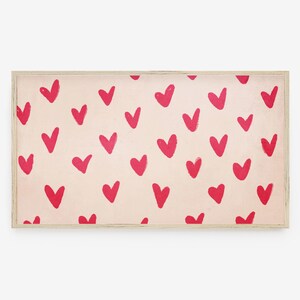 May include: A framed print with a pink background and a repeating pattern of red hearts.