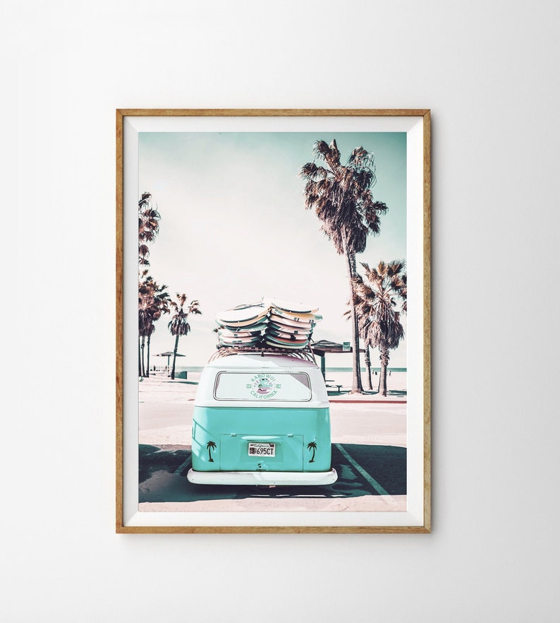 May include: A vintage light blue van with surfboards strapped to the roof parked in front of palm trees. The van has a sticker that says "Surf City California" and a license plate that says "495CT".