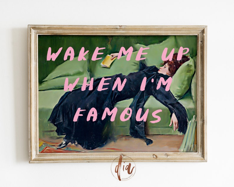 May include: A framed painting of a woman lying on a green couch. The woman is wearing a black dress and has red hair. The text "WAKE ME UP WHEN I'M FAMOUS" is written in pink letters on the painting.