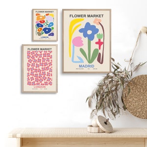 May include: Three framed prints with the title "Flower Market" and the cities Lisbon, Madrid, and London. Each print features a different abstract floral design in pink, blue, green, yellow, and red.