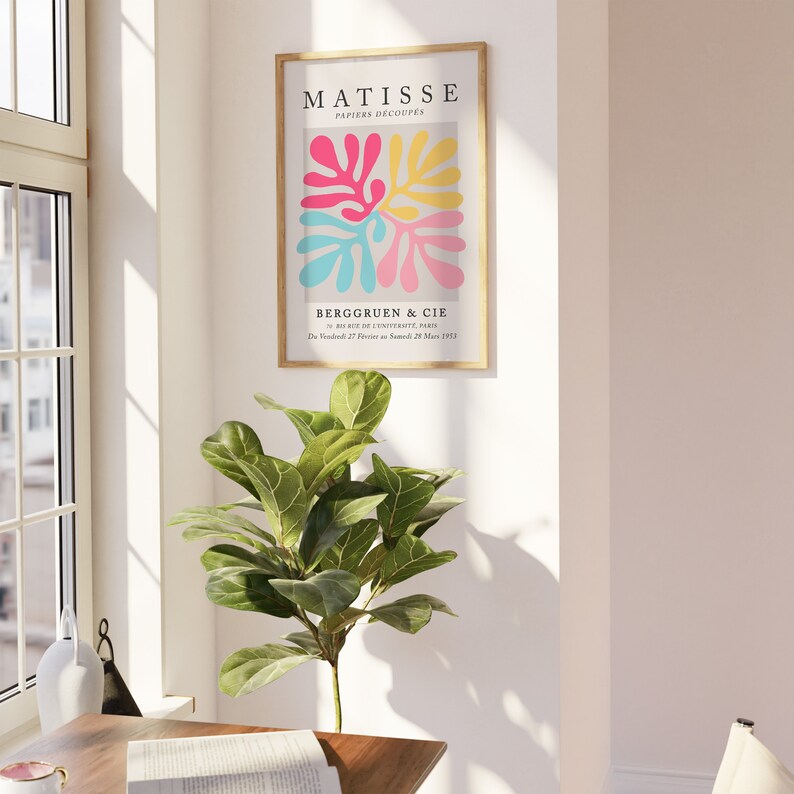 Pode incluir: Uma impress&atilde;o emoldurada de uma obra de arte de Matisse intitulada "Papiers Decoupes" que apresenta formas abstratas em rosa, amarelo e azul. A impress&atilde;o est&aacute; em uma moldura de madeira e tem o texto "BERGGRUEN & CIE" e "Du Vendredi 27 Fevrier au Samedi 28 Mars 1953" na parte inferior.