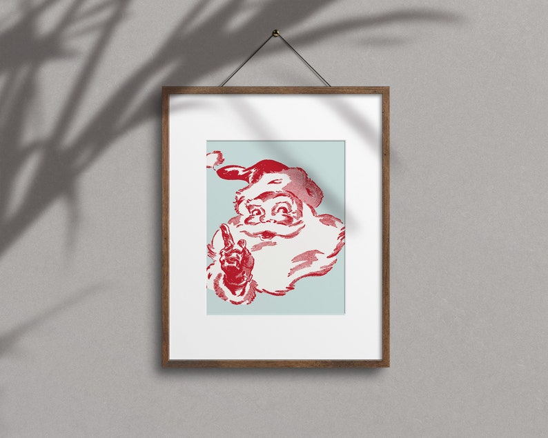 May include: A framed print of a vintage illustration of Santa Claus with a red hat and beard, against a light blue background. He is smiling and pointing with his index finger.