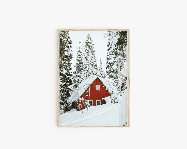 Op de afbeelding: Een rode hut met een groen dak ligt verscholen in een besneeuwd bos. De bomen zijn bedekt met sneeuw en de grond is bedekt met een dikke laag witte sneeuw.