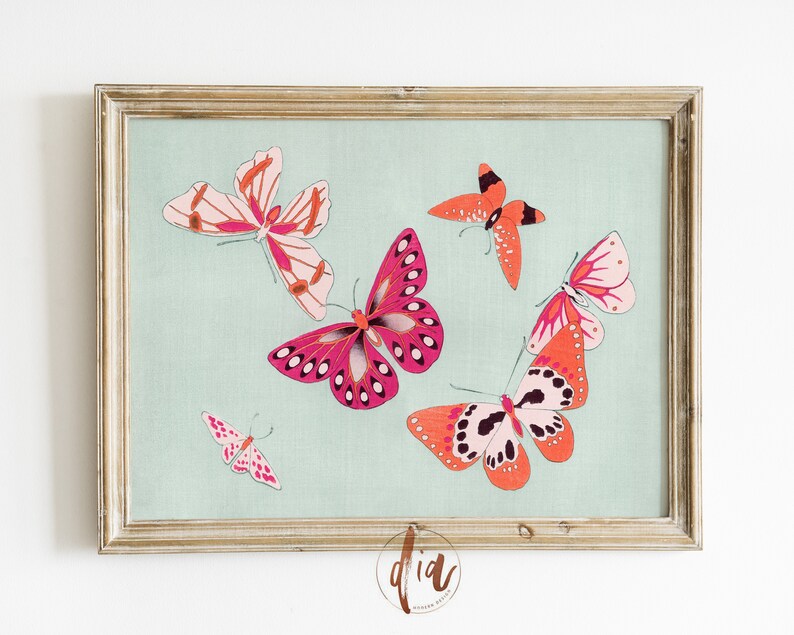 Puede incluir: Una impresi&oacute;n enmarcada que muestra varias mariposas en tonos rosa y naranja sobre un fondo azul claro. Las mariposas, de diferentes tama&ntilde;os y orientaciones, est&aacute;n enmarcadas en un marco dorado, ideal para la decoraci&oacute;n de paredes.