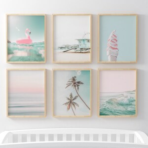 May include: Six framed prints with a beach theme. The prints feature a pink flamingo float, a beach scene with a lifeguard stand, a pink and white ice cream cone, a pink and blue sunset over the ocean, palm trees against a blue sky, and a wave crashing in the ocean.
