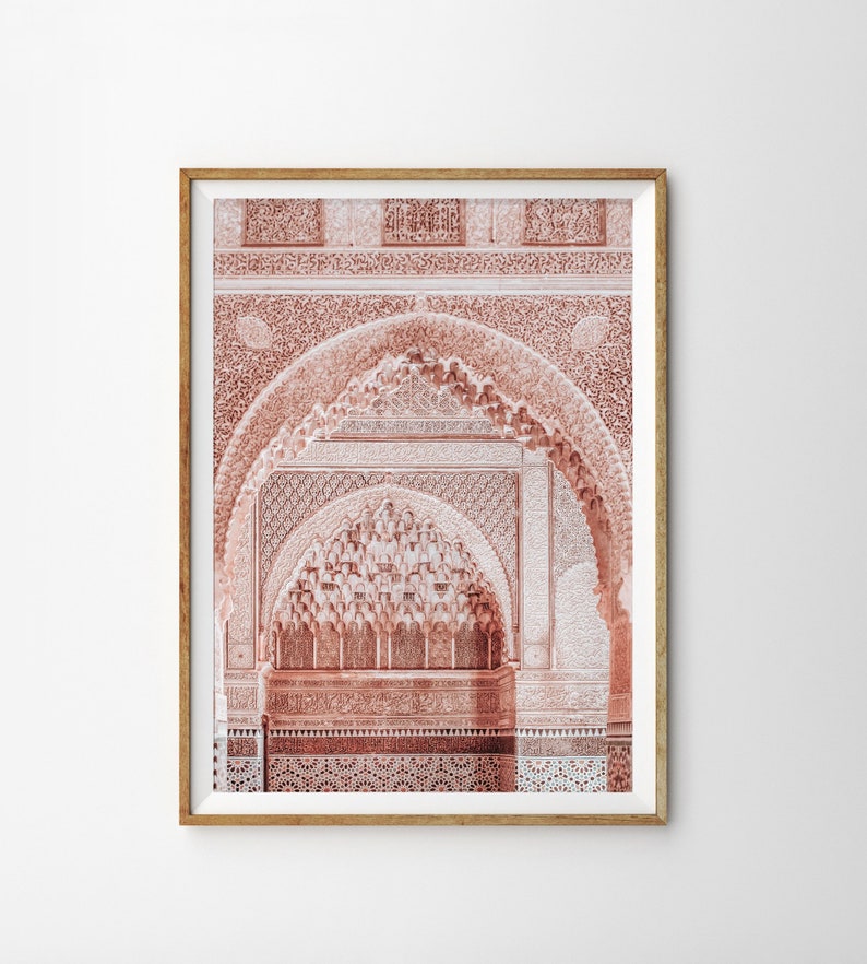 May include: A framed photograph of a pink and white intricate archway with detailed carvings. The archway is made of stone and has a traditional Moroccan design.