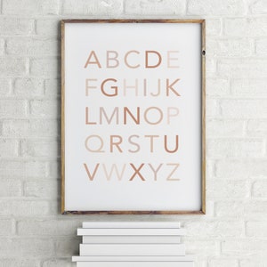 May include: A framed print of the alphabet in a neutral color palette. The letters are in a simple, sans-serif font and are arranged in rows. The letters are a gradient of brown shades, with the lightest shade at the top and the darkest shade at the bottom.