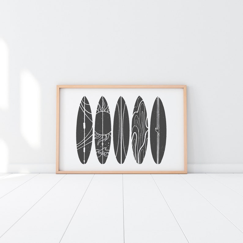 May include: A framed print of six black and white surfboards with different designs. The surfboards are arranged in a row against a white background.