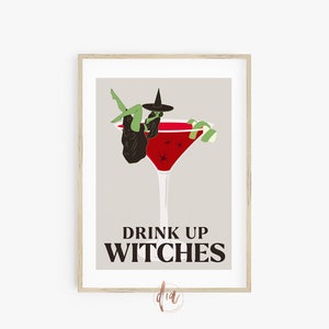 May include: A framed print with a witch sitting in a red cocktail glass with a lime garnish. The text "Drink Up Witches" is below the glass.