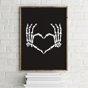 May include: A black and white printable art print featuring a pair of skeleton hands forming a heart shape.