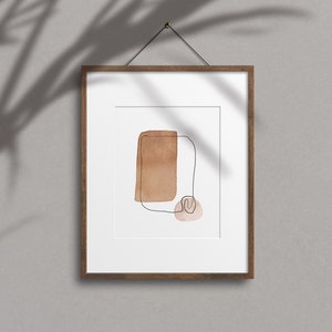 Op de afbeelding: Een ingelijst abstract kunstprint met een bruine aquarel vorm en een dunne zwarte lijn tekening. De print is op een witte achtergrond en heeft een houten lijst.