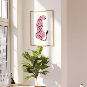 May include: A framed print of a pink cheetah with black spots sitting on a white background.