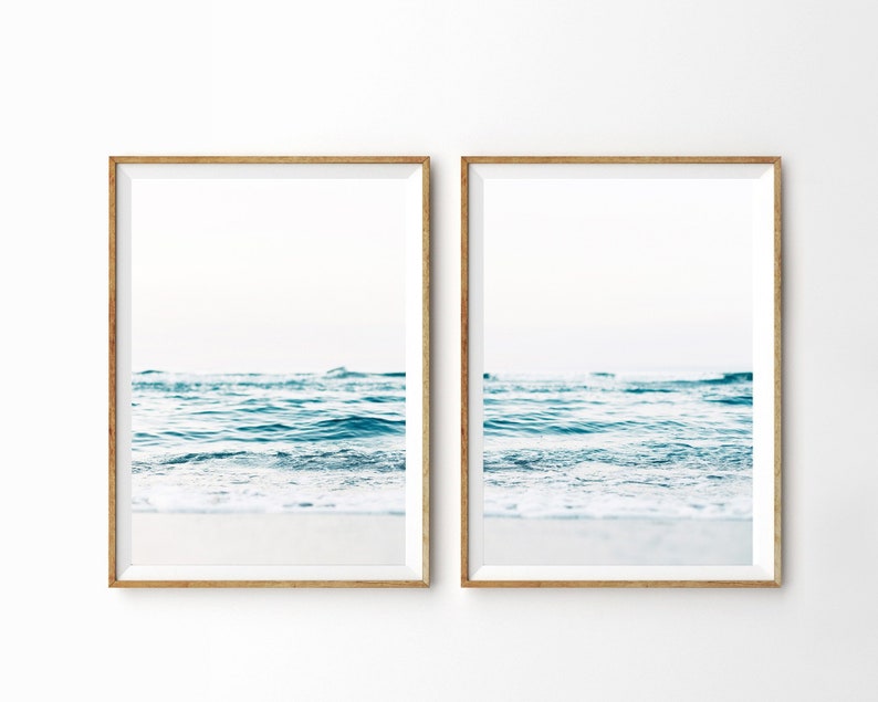 May include: Two framed prints of a seascape with blue water and white foam crashing on the shore.