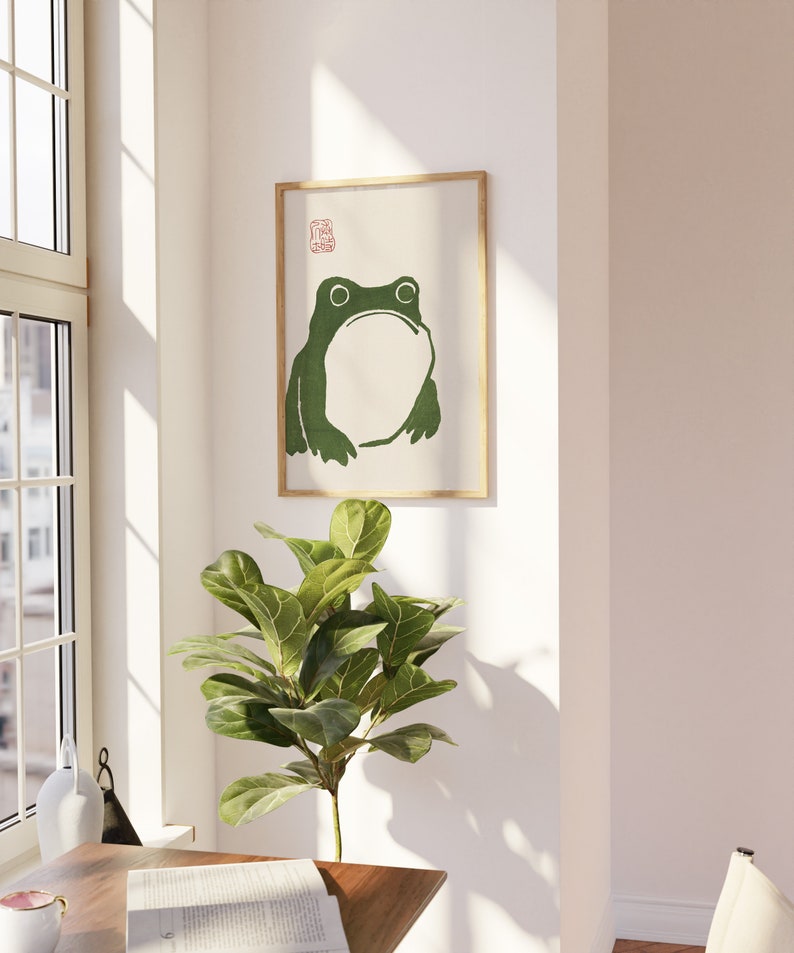 May include: A framed print of a green frog with a white background. The print has a red stamp in the top right corner.