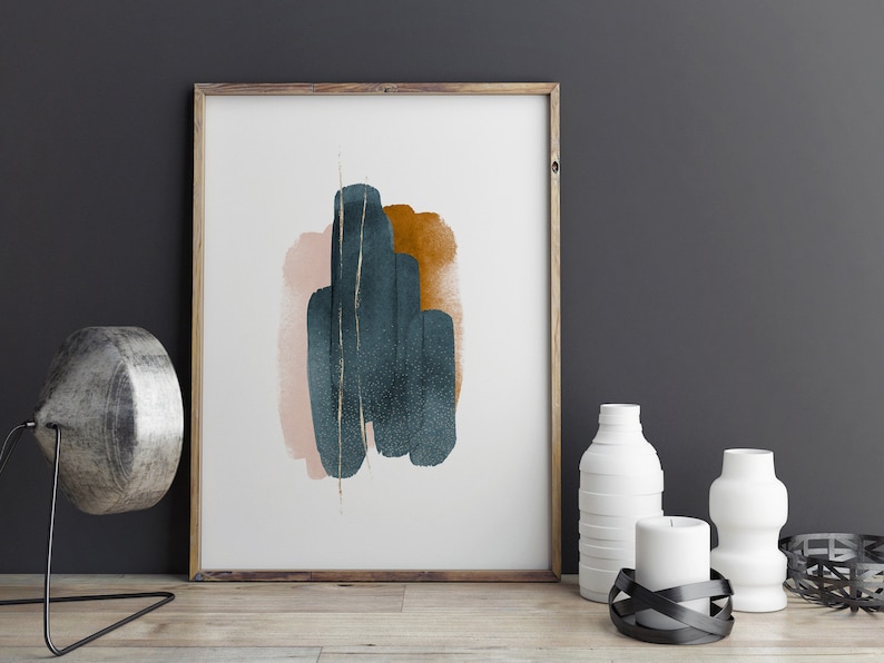 May include: Abstract art print featuring a teal, pink, and gold design, framed in wood. The print is displayed against a dark grey wall.