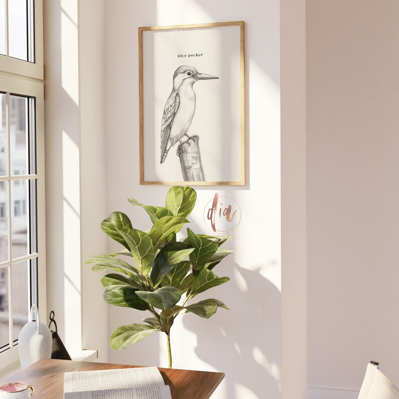 May include: A black and white illustration of a bird perched on a branch. The bird is labeled "kiwi pecker". The illustration is framed in a light wood frame and hanging on a white wall.