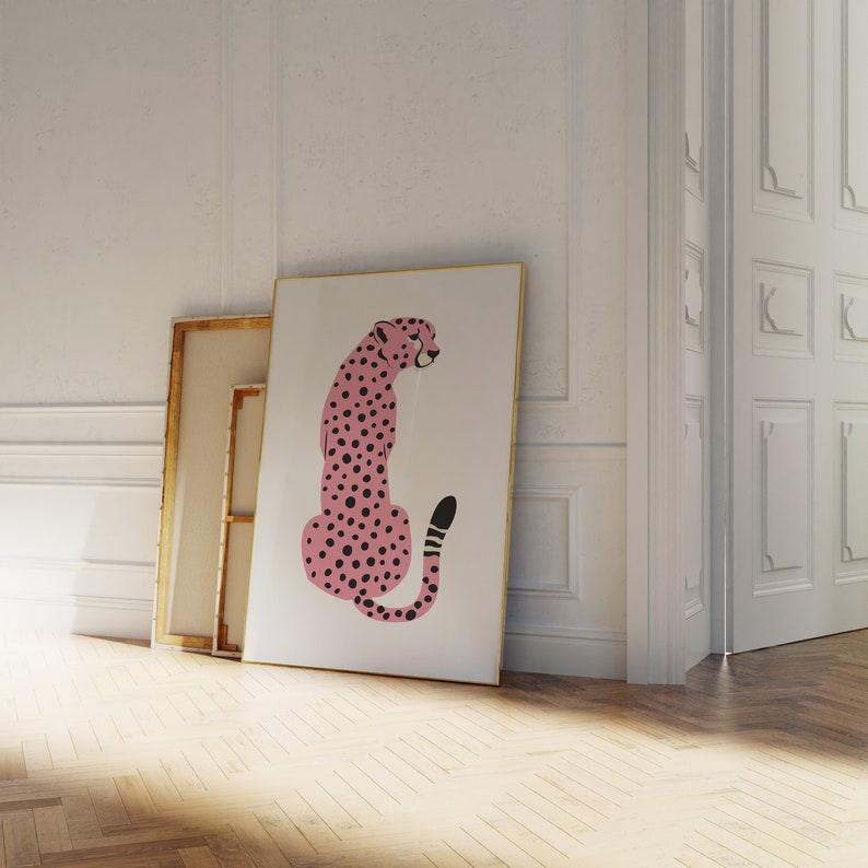 May include: A pink cheetah with black spots sitting on a white background. The cheetah is facing to the left and has a black tail with a white tip.