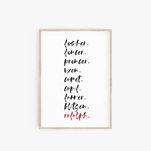 Op de afbeelding: Een zwart-witte printbare wandkunstprint met de namen van Santa's rendieren in een verticale lijst. De namen zijn geschreven in een gestileerd lettertype. De laatste naam, "rudolph", is geschreven in rood.