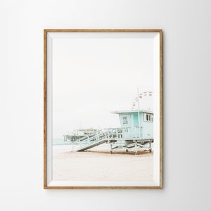 May include: A light blue lifeguard stand with a wooden ramp and stairs on a sandy beach. The stand has a sign that reads "Lifeguard Station 15". A pier is visible in the background.