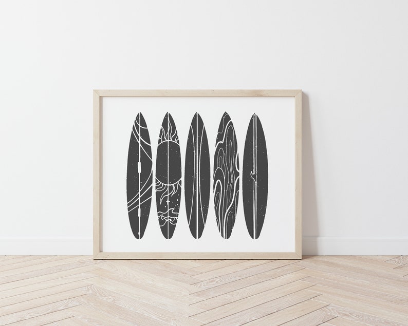 May include: A framed print of six black and white surfboards with different designs. The surfboards are arranged vertically in a row. The background is white.