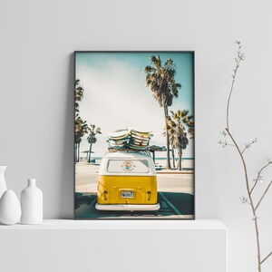 May include: A yellow vintage van with surfboards on the roof parked in front of palm trees on a sunny day. The van has a license plate that says "SURF CITY".