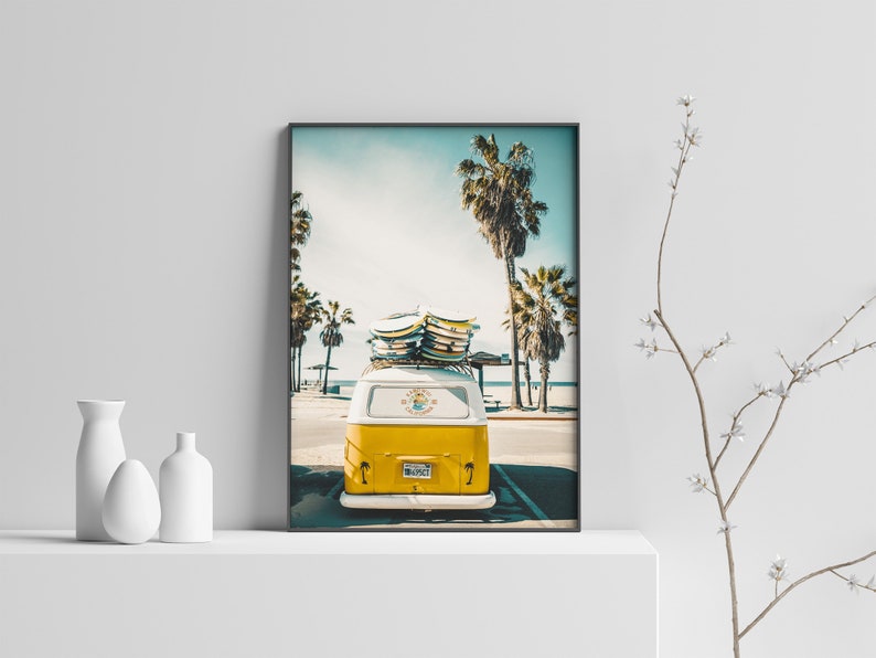 May include: A yellow vintage van with surfboards on the roof parked in front of palm trees on a sunny day. The van has a license plate that says "SURF CITY".