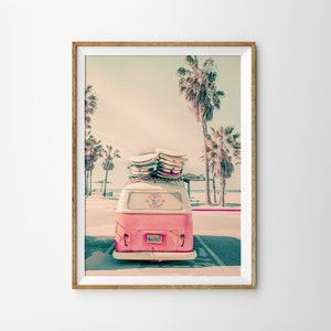 May include: A pink vintage van with surfboards on the roof parked in front of palm trees. The van has a sticker that says "California Surf Club".