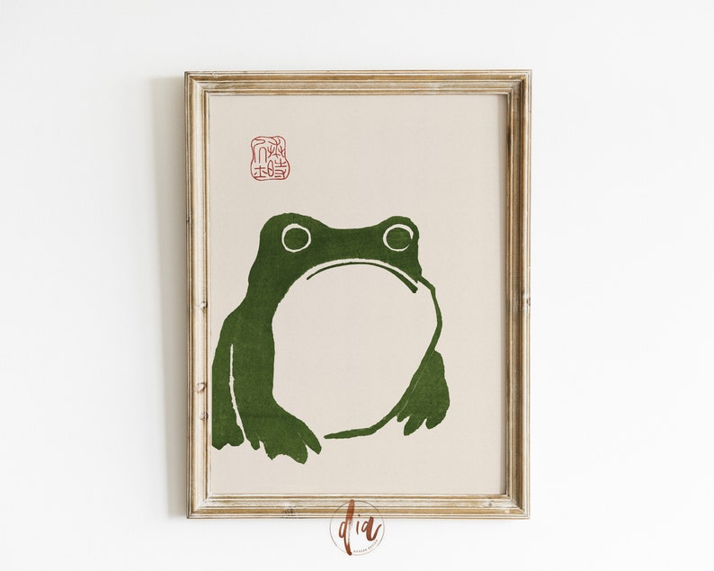 May include: A framed print of a green frog silhouette on a beige background. A red stamp with Japanese characters is in the top right corner.