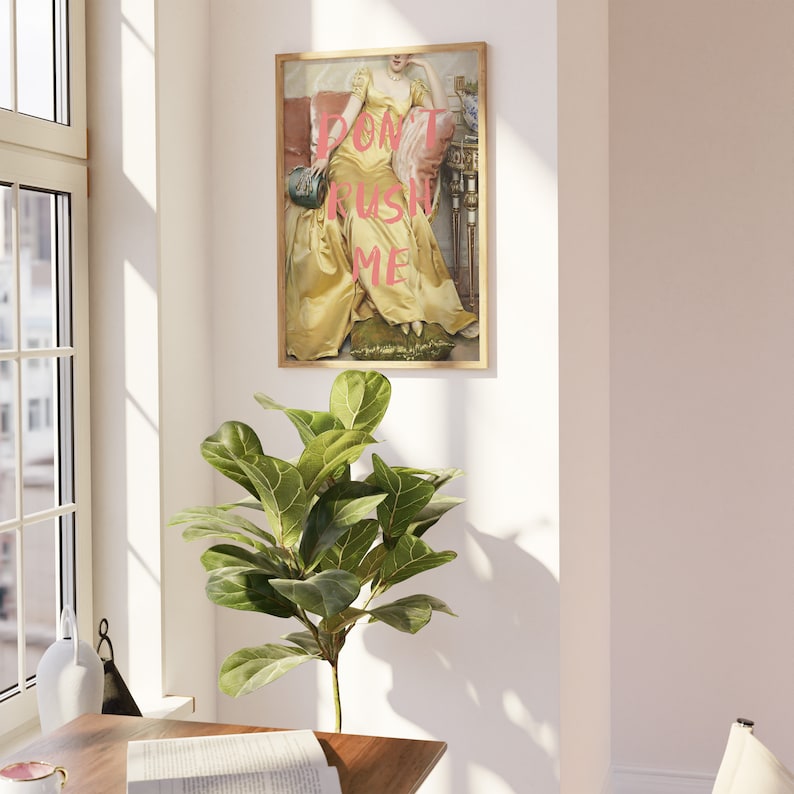 May include: A framed print of a woman in a yellow dress sitting on a chair. The text "DON'T RUSH ME" is superimposed on the image in pink.