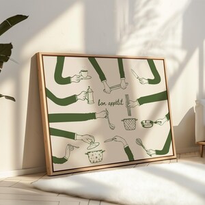 May include: A framed art print featuring a beige background with green line drawings of hands holding various kitchen utensils. The phrase "bon app&eacute;tit" is written in cursive. The artwork includes a coffee cup, a knife, and a whisk.