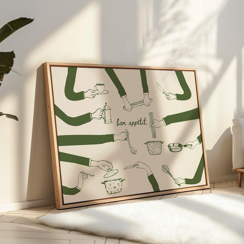 May include: A framed art print featuring a beige background with green line drawings of hands holding various kitchen utensils. The phrase "bon app&eacute;tit" is written in cursive. The artwork includes a coffee cup, a knife, and a whisk.