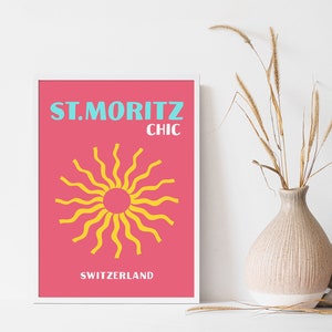 May include: A pink and white framed poster with the text "ST. MORITZ CHIC SWITZERLAND" and a yellow sun graphic.