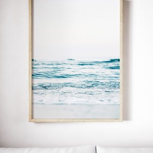 Peut inclure: Une photographie encadr&eacute;e d'un oc&eacute;an bleu avec des vagues blanches mousseuses qui se brisent sur le rivage.